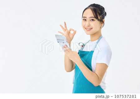 電卓を使うエプロン姿の若い主婦 107537281