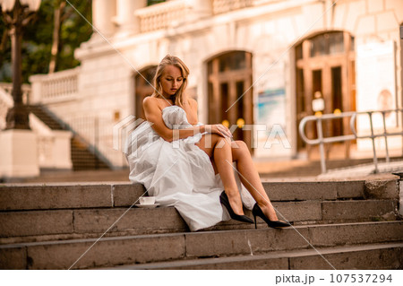 Woman city blanket. Morning in the big city. A blonde woman in a white blanket is enjoying in the city center. Photographed for social media 107537294