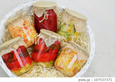 Variety glass jars of homemade pickled or fermented vegetables in box on white background. Fermented food. Place for text. Top view. Variety glass jars of homemade pickled or fermented vegetables in box on white background. Fermented food. Place for text. Top view. 107537371