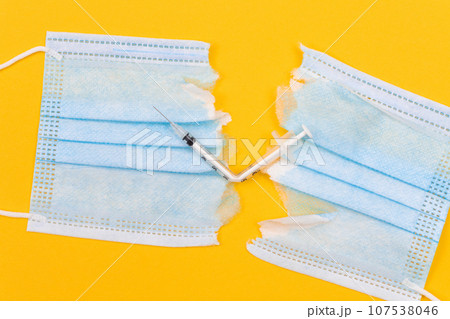Broken Medical Syringe and Torn Medical Face Mask Broken Medical Syringe and Torn Medical Face Mask 107538046
