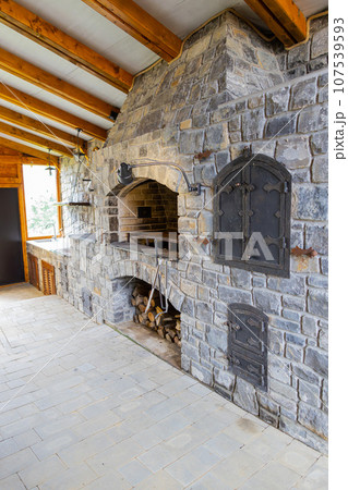 Stone restaurant barbecue firewood, open brick oven cooking food dishes on fire indoors in backyard 107539593