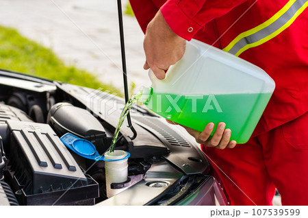 Service worker man pours car fluid windscreen green cleaning washer glass summer or winter cleaner Service worker man pours car fluid windscreen green cleaning washer glass summer or winter cleaner 107539599