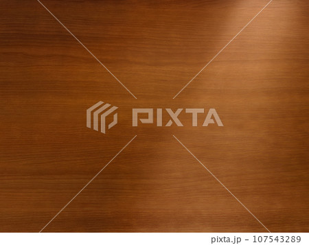 繊細な茶色の木目の机の天板に右上から光が斜めに差す背景画像 107543289