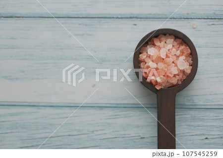 Raw dried pink Himalayan salt in a wooden spoon  107545259