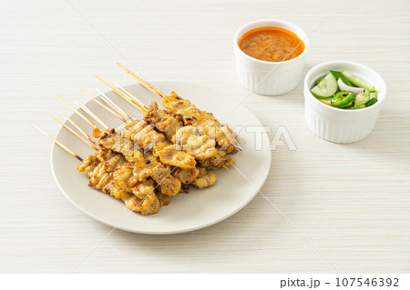 Pork satay with peanut sauce pickles which are cucumber slices and onions in vinegar 107546392