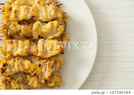 Pork satay with peanut sauce pickles which are cucumber slices and onions in vinegar 107546394