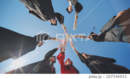 College graduates join hands with their diplomas. The concept of friendship. College graduates join hands with their diplomas. The concept of friendship. 107546933