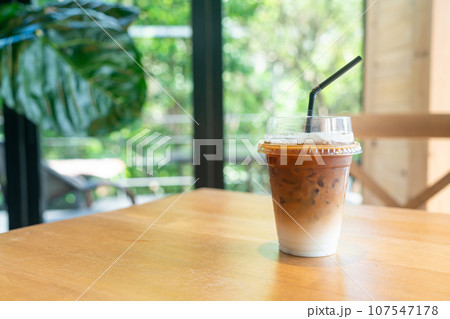 iced latte coffee in takeaway glass on table in coffee shop 107547178