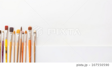 Paint brushes on white background. A row of colorful paint brushes with wooden handles and different types of bristles, arranged on a plain white background. The bristles show various hues, indicating 107550590