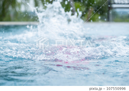 Child jumping in swimming pool, water splashing. Children in swimming pool having fun during family summer vacation. Child jumping in swimming pool, water splashing. Children in swimming pool having fun during family summer vacation. 107550996