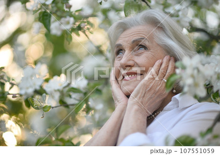 Close-up portrait of smiling elderly woman posing in summer park 107551059