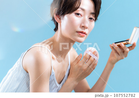 ブルーバックでUVケアをするミドルの女性 ブルーバックでUVケアをするミドルの女性 107552782