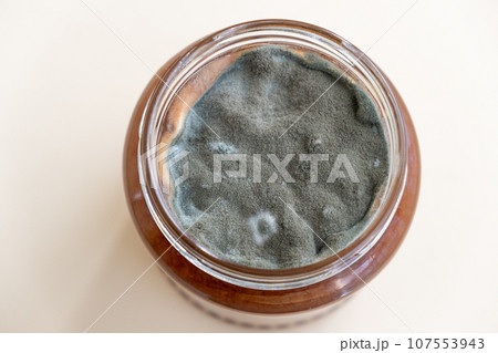 Open jar with sweet jam and mold on a white background. Mold in a jar of raspberry jam. Hazardous to health.  Open jar with sweet jam and mold on a white background. Mold in a jar of raspberry jam. Hazardous to health.  107553943
