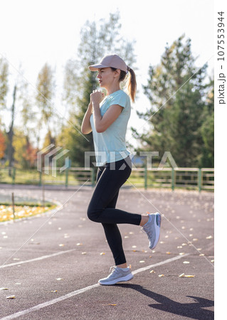 A young beautiful woman in sportswear plays sports at a local stadium. Exercise, jog and exercise at the beginning of the day. Healthy and active lifestyle. A young beautiful woman in sportswear plays sports at a local stadium. Exercise, jog and exercise at the beginning of the day. Healthy and active lifestyle. 107553944