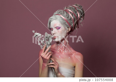 Cold beauty. Halloween model with dried flower. Witch woman, fashion beauty studio portrait Cold beauty. Halloween model with dried flower. Witch woman, fashion beauty studio portrait 107554008