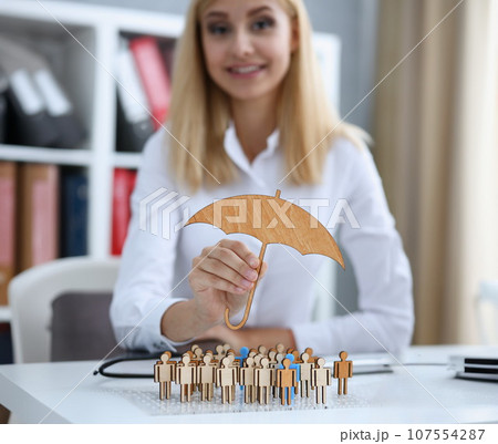 Smiling Business woman in hand holds a miniature umbrella Smiling Business woman in hand holds a miniature umbrella 107554287