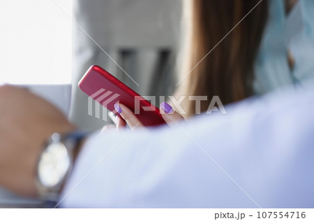 Smartphone in a woman's hand on a red window Smartphone in a woman's hand on a red window 107554716