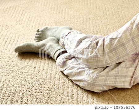 寝巻姿で寝転んだ、靴下を履いた足 107556376