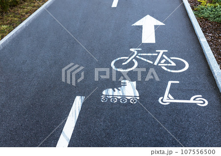 Bicycle road with painted white signs bicycle, roller skates, scooter and arrow direction of movement 107556500
