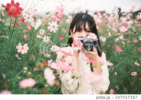 花畑で写真を撮る女性 107557387