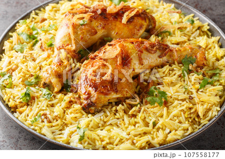 Bengali style roast chicken legs with fried onions served with spicy pilaf close up in a plate. Horizontal Bengali style roast chicken legs with fried onions served with spicy pilaf close up in a plate. Horizontal 107558177