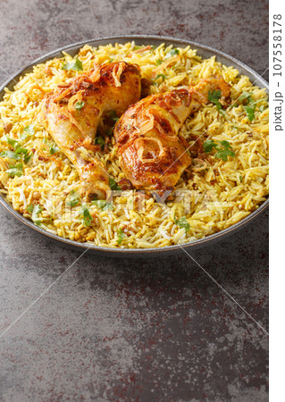 Bangladeshi spicy roast chicken served with aromatic pilaf close-up in a plate. Vertical Bangladeshi spicy roast chicken served with aromatic pilaf close-up in a plate. Vertical 107558178