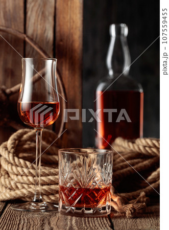 Crystal glass, snifter, and bottle with rum, cognac, or whiskey. Crystal glass, snifter, and bottle with rum, cognac, or whiskey. 107559455