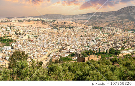 Beautiful panoramic view of the old Medina in Fes, Morocco (Fes El Bali Medina), a sea of buildings made of earthy tones. It's a bustling maze of life, with people and markets nestled in its heart Beautiful panoramic view of the old Medina in Fes, Morocco (Fes El Bali Medina), a sea of buildings made of earthy tones. It's a bustling maze of life, with people and markets nestled in its heart 107559820