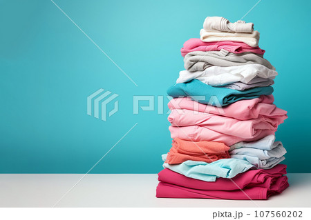Pile of clothes ready for laundry. Stack of colorful clothes. Laundry day, fabric recycling concept. Fashion industry pollution, sustainability, up cycling, secondary clothing, reuse. Copy space 107560202