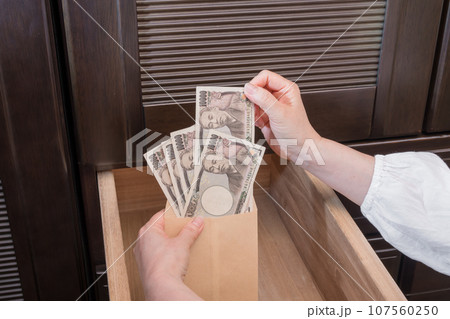 【主婦がたんすの引き出しに封筒入りの一万円札を隠す】 107560250
