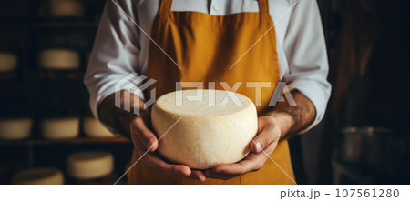 A man with a passion for cheese showcases his artisanal masterpiece in his hands. 107561280