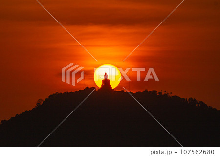 The sun circles in the red sky behind the Big Buddha..Amazing Phuket big Buddha in circle of the sun in red sky..The beauty of the statue fits perfectly with the charming nature. .red sky background The sun circles in the red sky behind the Big Buddha..Amazing Phuket big Buddha in circle of the sun in red sky..The beauty of the statue fits perfectly with the charming nature. .red sky background 107562680