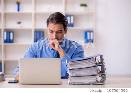 Young male employee and too much work in the office Young male employee and too much work in the office 107564596