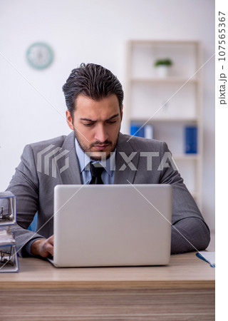 Young male employee and too much work in the office 107565367