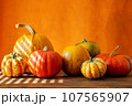 A row of orange pumpkins on a wooden surface with an orange background and a place to copy 107565907
