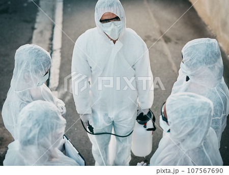 Covid pandemic outbreak team of doctors or medical workers wearing protective ppe to prevent spread of virus outside. Group of scientists wearing hazmat suit for corona or ebola disease in the street 107567690