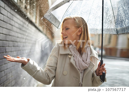 Smile, happy woman and rain feel in the city with umbrella, freedom and happiness on holiday. Winter weather, raining and urban street with a young female person on a sidewalk and vacation outdoor 107567717