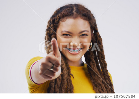 Woman, studio portrait and smile with thumbs up for agreement, vote or hand for review with happiness by background. Girl, model and sign for opinion, yes or thank you for motivation, win and success 107567884