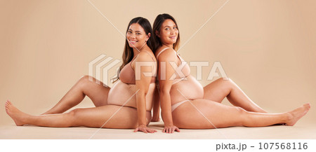 Friends, pregnancy and studio portrait for underwear, smile and women sitting together for support on floor. Happy future mom, pregnant or solidarity for health, love or healthy stomach by background Friends, pregnancy and studio portrait for underwear, smile and women sitting together for support on floor. Happy future mom, pregnant or solidarity for health, love or healthy stomach by background 107568116