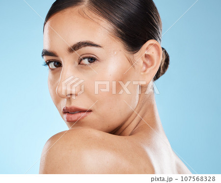 Portrait, beauty and shoulder with a model woman in studio on a blue background for natural skincare. Face, skin and cosmetics with an attractive young female posing to promote a luxury product 107568328