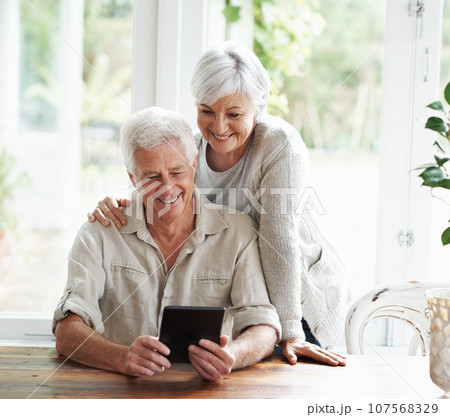Tablet, happy old couple and online in home with social media, reading news app and ebook. Retirement, senior man and woman with digital technology for subscription, streaming and network connection 107568329