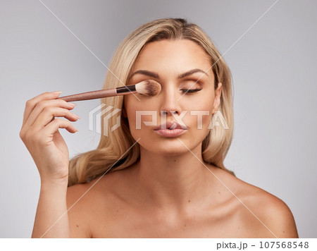 You are imperfect, permanently and inevitably flawed. Studio shot of a beautiful young woman holding a makeup brushe against a grey background. 107568548