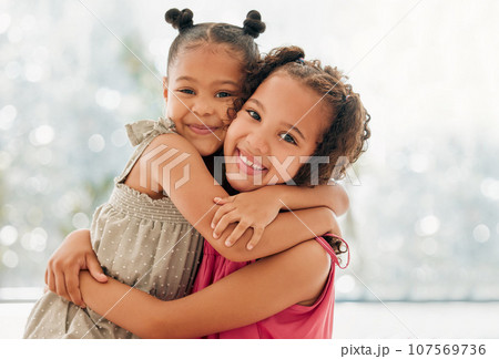Cute, adorable and sweet girls hugging and bond with a happy and healthy childhood growing at home. Portrait of innocent and loving sisters with a bright smile, affection and relaxing in the house 107569736