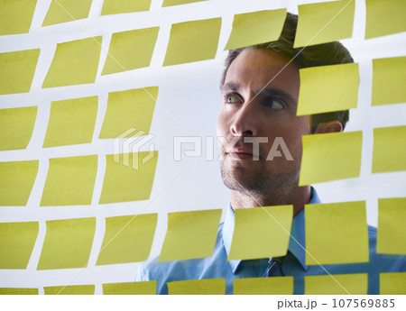 Businessman, face and thinking in planning, sticky note or brainstorming tasks on glass board at office. Thoughtful man contemplating business decision, strategy or schedule in wonder at workplace Businessman, face and thinking in planning, sticky note or brainstorming tasks on glass board at office. Thoughtful man contemplating business decision, strategy or schedule in wonder at workplace 107569885