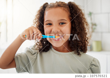 Toothbrush, brushing teeth and portrait of a child in a home bathroom for dental health and wellness with smile. Face of Latino girl kid learning to clean her mouth for morning routine and oral care 107570321