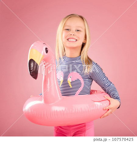 Safety, happy and portrait of girl and pool float for swimming, summer break and relax. Youth, funny and inflatable with child and flamingo ring for pool, smile and beach holiday on pink background Safety, happy and portrait of girl and pool float for swimming, summer break and relax. Youth, funny and inflatable with child and flamingo ring for pool, smile and beach holiday on pink background 107570425
