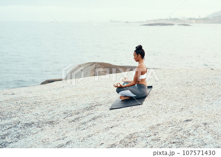 Yoga, meditation and woman on a beach with lotus pose, wellness and fitness. Pilates, sea and female person on sand with peace in nature feeling relax and calm with spiritual and holistic mockup 107571430