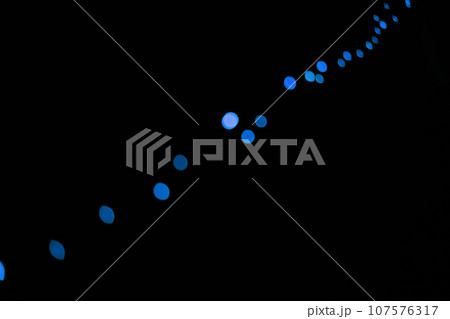 Bokeh, neon blue dots on black background and lights with pattern, texture and mockup with cosmic aesthetic. Night lighting, sparkle particles and glow on dark wallpaper with space, shine and flare. 107576317