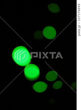 Green light, bokeh and glow on dark background on a mockup space. Blur, black backdrop and defocused shine, sparkle or abstract glitter at night for Christmas, holiday or party with magic color dots 107576649
