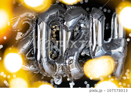 Holiday bokeh garland Happy new year 2024 metallic balloons with confetti on dark black background. Greeting card silver foil balloons numbers Christmas holiday concept. Celebration party 107578013